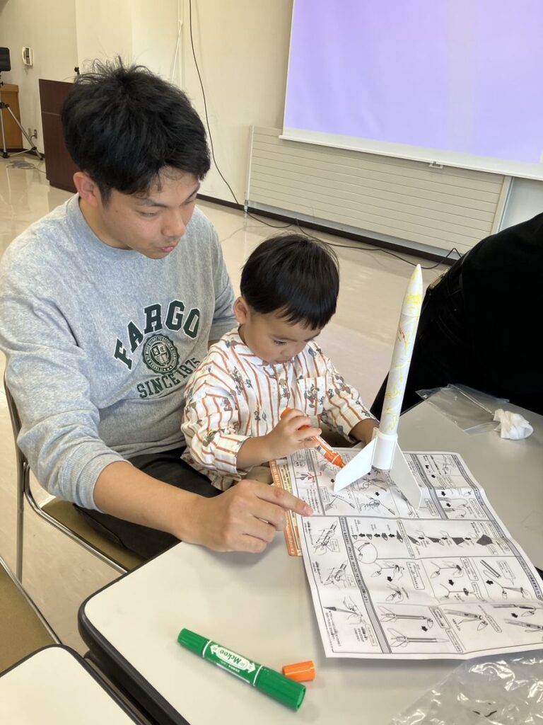 説明書を見ながらロケットを組み立てる親子